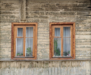 Fototapeta na wymiar Old wooden house with two windows painted faded white