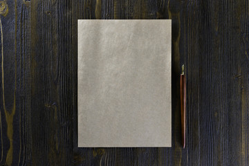 Mockup of blank vintage letterhead and pen at brown wooden background.
