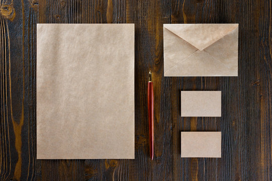 Mockup of vintage stationery set including leterhead, business cards and envelope at wooden table background.