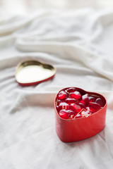 Old box in heart shape on white background, on white cloth, in box red sweet jelly beans, Valentine's day, women's day, gifts
