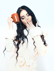 sexy yawning girl in beige velour bathrobe holding cup