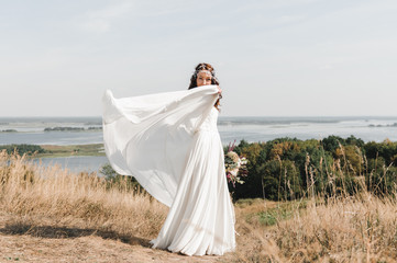 Fototapeta na wymiar Невеста в свадебном платье на горе с видом на просторный разлив реки