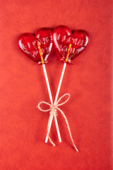 Two lollipop in heart shape on red background.