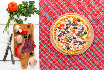 fresh pizza in a rustic Italian style with jerky olives mushrooms and three kinds of cheese on a light wooden background