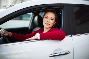 A young woman driving her white car.