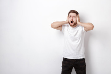 indignant young man with dark hair and beard in t-shirt shouts a