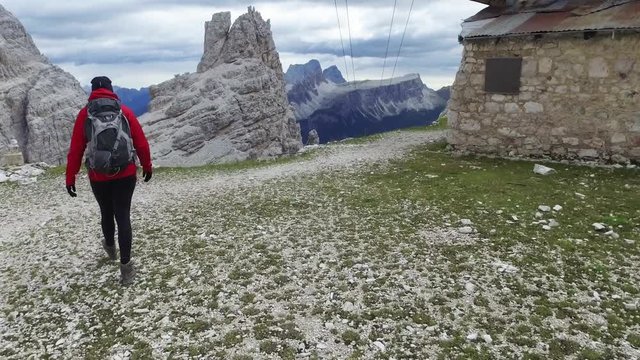 Young female hiker walks in Italian Dolomites. Handheld footage from a rocky trail in Dolomites mountains.