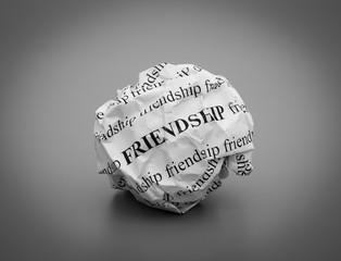 Crumpled paper ball with words Friendship on gray background