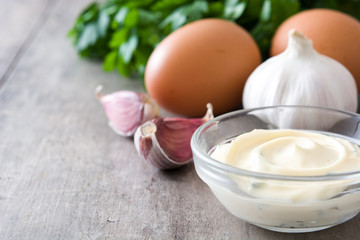 Aioli sauce and ingredients on wooden background
