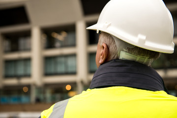 Construction worker / building inspector surveying a tall building.