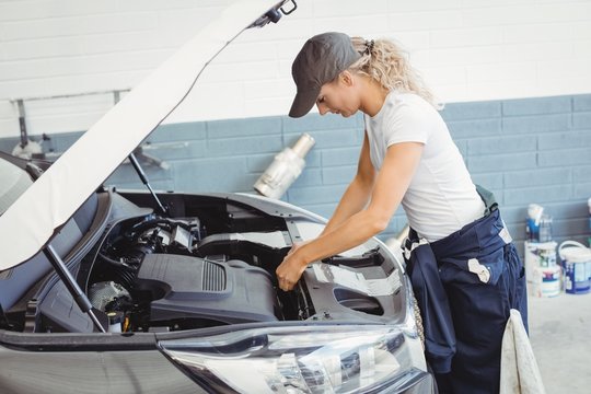Female mechanic servicing car