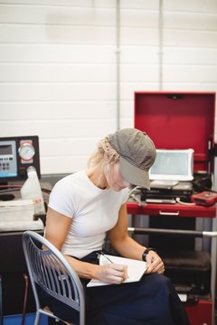 Female mechanic writing on notebook