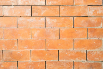 the old and dirty orange brick wall in warm or hot color tone/style with black stain for background texture