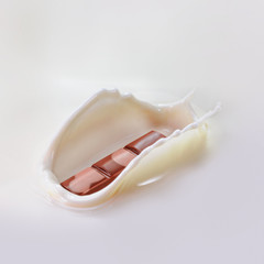 Chocolate falling into splashing milk. Isolated on white. High resolution photo.