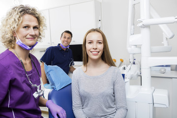 Smiling Female Patient With Dentists In Clinic