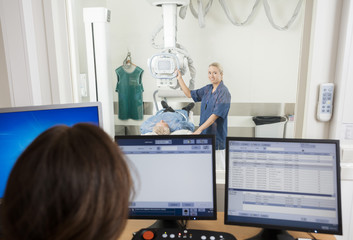 Radiologist Taking Patient's Xray While Colleague Using Computer