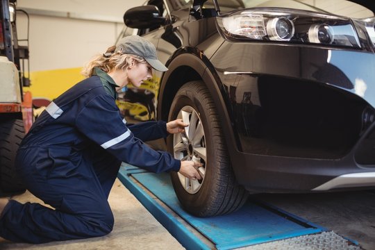 Female mechanic examining a car wheel