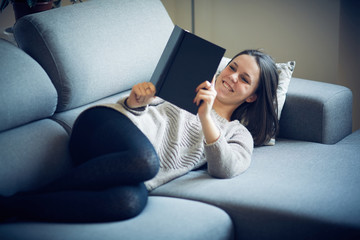 Ragazza legge libro sul divano a casa