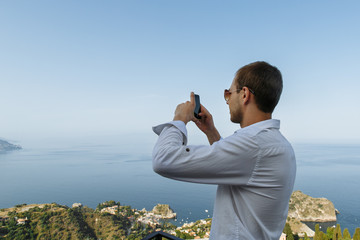Tourist taking photo of beautiful sea lagoon on smartphone in Italy