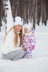 beautiful mother and daughter in a winter forest for a walk. Mom keeps daughter in her arms