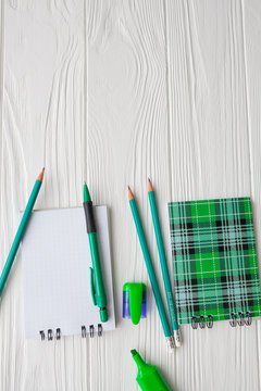 green stationery. notebooks, pens, pencils on a white background 