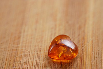 Amber heart on wooden board, scratched board by knife
