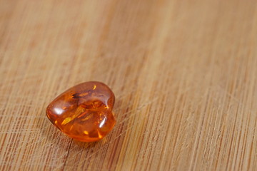 Amber heart on wooden board, scratched board by knife