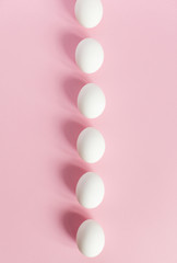 White Easter eggs on a light pink background