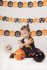 cute child with a witch costume playing with Halloween decoration