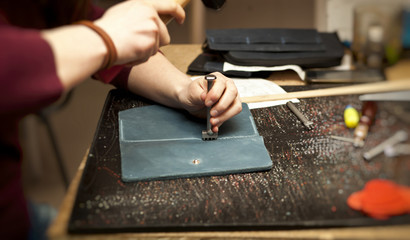 The young woman works with leather