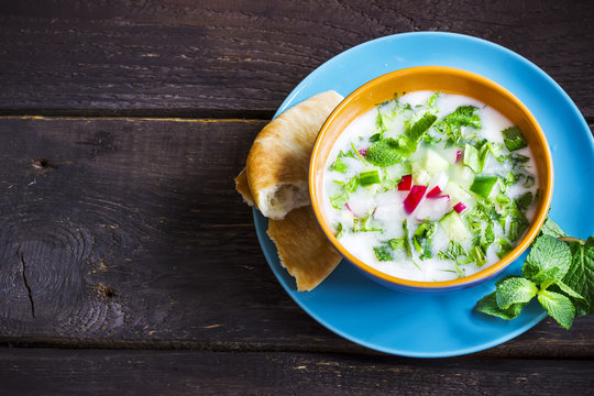 Azerbaijani/russian cold soup with greens on dark rustic background.