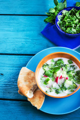 Azerbaijani/russian cold soup with greens on blue wooden background.