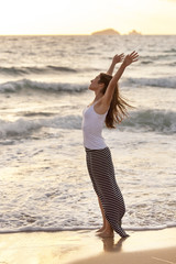 Fototapeta na wymiar young cheerful woman stretching barefoot on the sea shore