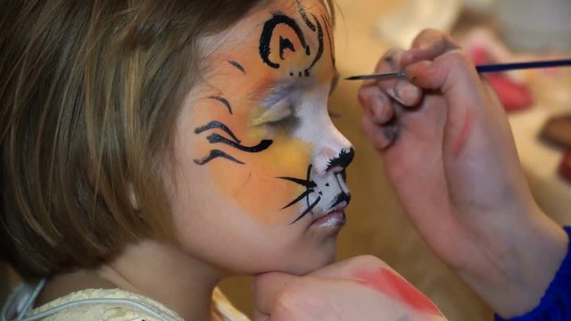 On the face of the child colors paint the face of a tiger.
