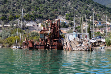 Fototapeta na wymiar Seen from the sea sunken by the coast of Lefkada Island, Greece old ruined boats and a rusty dredge