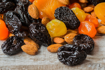 prunes, dried apricots, dried mandarins and almonds on a light wooden background
