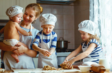 happy family in kitchen. mother and children preparing dough, bake cookies.