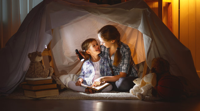 mother and child daughter with a book and a flashlight before going to bed