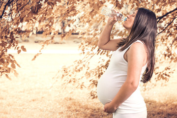 Pregnant woman drinking watter from bottle - Powered by Adobe