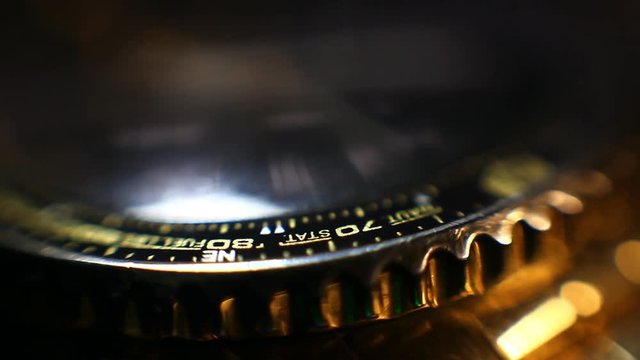 Rotating golden wristwatch with chronograph close up