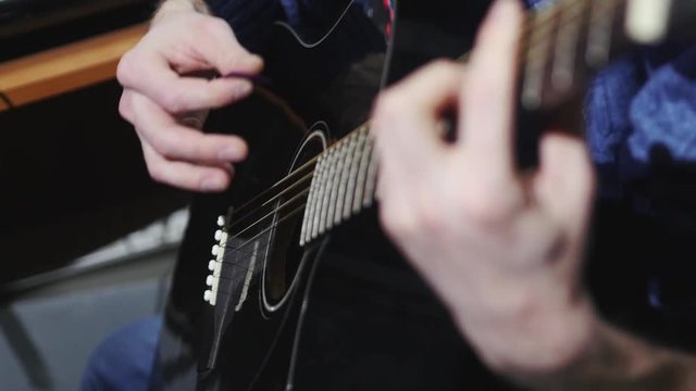 Man playing black classic guitar mediator, slow motion