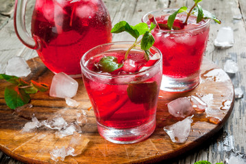Summer iced drink - tea or juice with ice and mint. On rustic wooden table, copy space