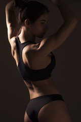 Sexy slim fit woman body. Muscled back. Sportswear. Dark background