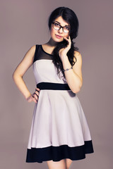Beautiful brunette caucasian business woman in classic dress and glasses. neutral grey background