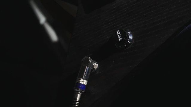 the hand of the guitarist inserts Jack into the guitar socket close up
