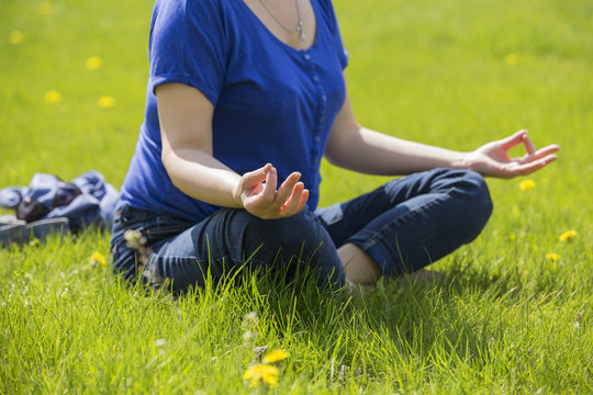 Beautiful Blonde Eldery Senior Woman Relaxing On A Grass In Park In Yoga Meditation. Casual Outfit