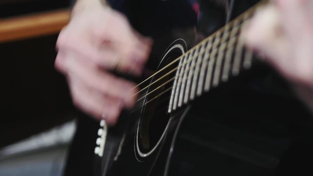 Man playing black classic guitar mediator, slow motionm close-up
