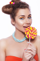 Beautiful brunette sweet woman with colorful make up and nail polish, and cute bun hairstyle. Eating lollipop. white background