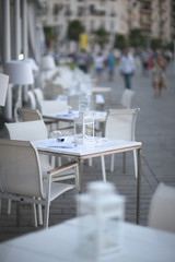 White cafe tables on the street of the spa town in the evening