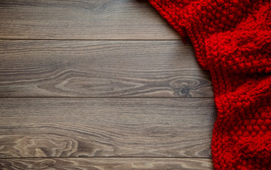 Knitted red blanket on a wooden background with copy space